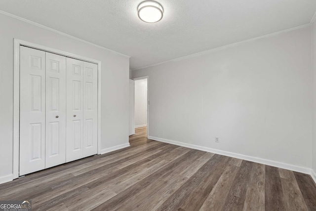 unfurnished bedroom featuring a closet, ornamental molding, a textured ceiling, and hardwood / wood-style flooring