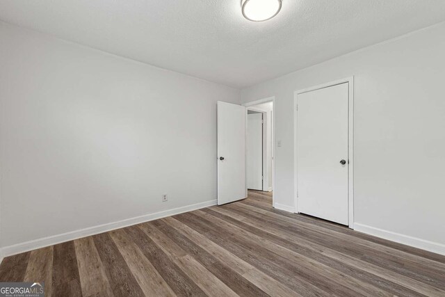 unfurnished bedroom with wood-type flooring, a textured ceiling, and a closet