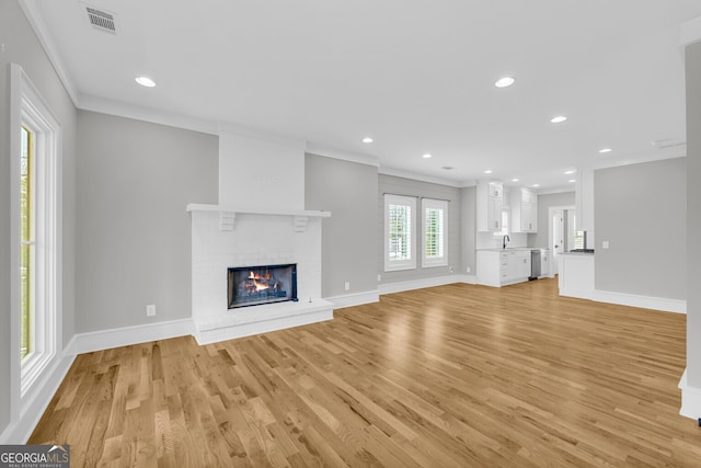 unfurnished living room with ornamental molding, a fireplace, and light hardwood / wood-style flooring