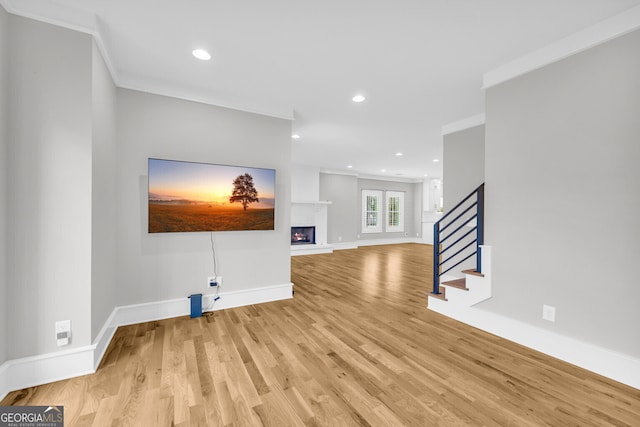 unfurnished living room with light wood-type flooring and ornamental molding