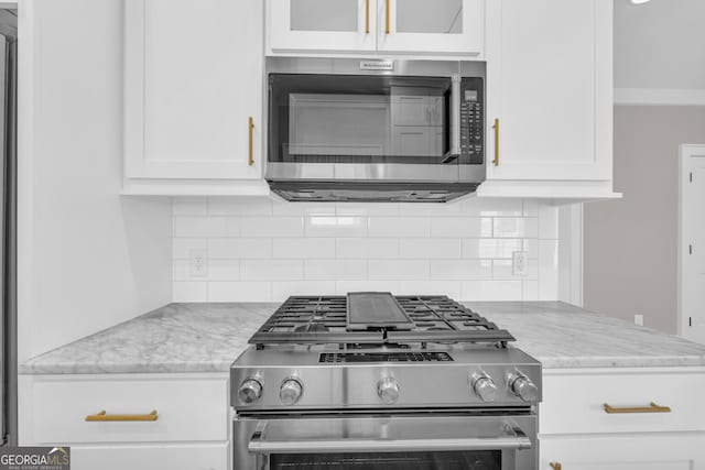 kitchen featuring decorative backsplash, white cabinetry, stainless steel appliances, and light stone counters