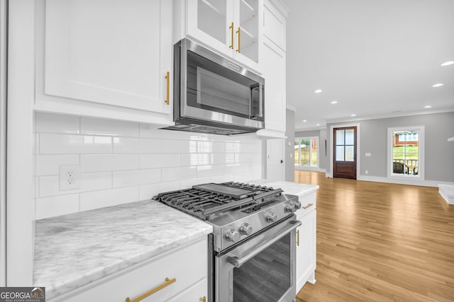 kitchen with tasteful backsplash, light stone counters, white cabinets, and stainless steel appliances