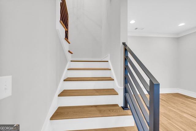 stairway featuring hardwood / wood-style floors and crown molding