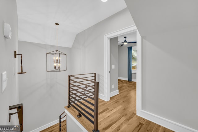 stairway with ceiling fan with notable chandelier, vaulted ceiling, and hardwood / wood-style flooring