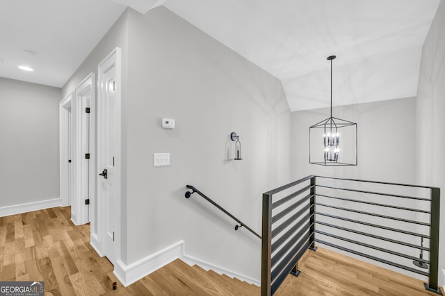 stairway featuring vaulted ceiling, a notable chandelier, and hardwood / wood-style flooring