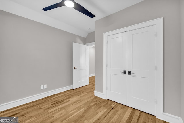 unfurnished bedroom with light wood-type flooring, a closet, vaulted ceiling, and ceiling fan