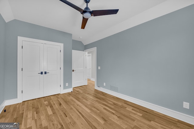 unfurnished bedroom featuring ceiling fan, a closet, light hardwood / wood-style floors, and lofted ceiling