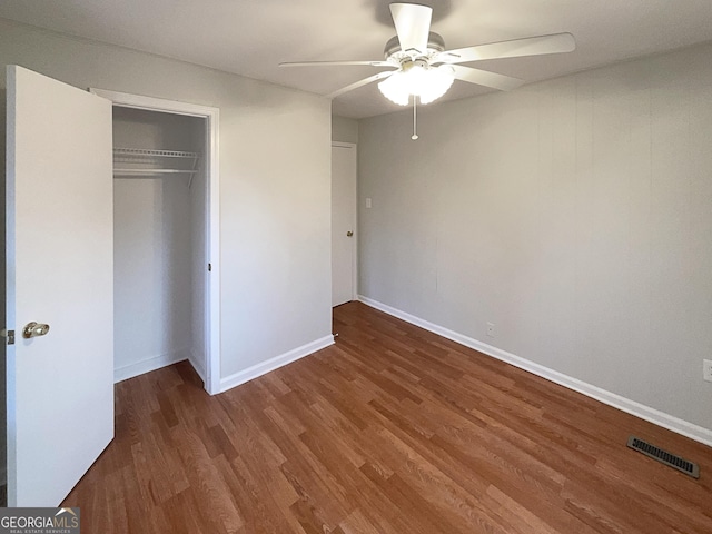 unfurnished bedroom featuring ceiling fan, dark hardwood / wood-style floors, and a closet