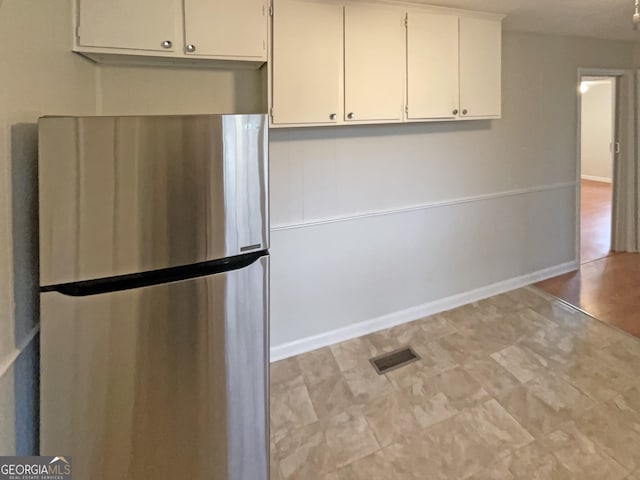 kitchen with white cabinetry and stainless steel fridge