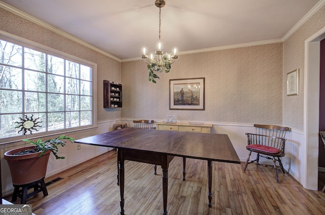 dining area featuring light wood-type flooring, crown molding, and an inviting chandelier