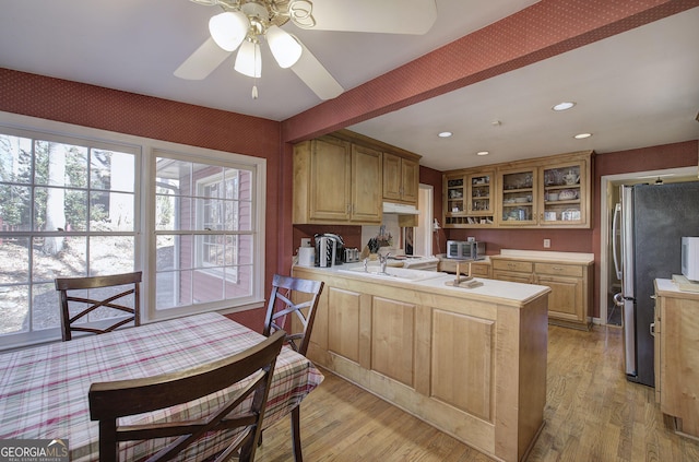 kitchen with light wood-type flooring, ceiling fan, kitchen peninsula, and stainless steel fridge