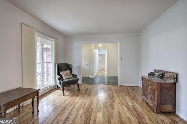 sitting room featuring baseboards, light wood-type flooring, and crown molding