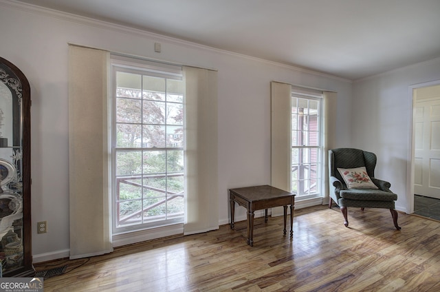 sitting room with ornamental molding, baseboards, a healthy amount of sunlight, and wood finished floors