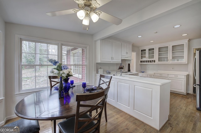 kitchen with glass insert cabinets, white cabinetry, light countertops, and light wood-style flooring