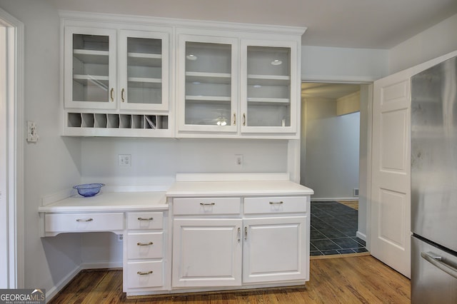kitchen with white cabinets, light countertops, dark wood-type flooring, and freestanding refrigerator