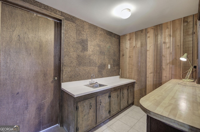 bathroom with sink, wooden walls, and tile patterned flooring