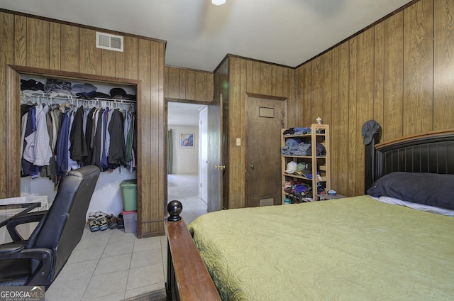 tiled bedroom featuring crown molding, wooden walls, and a closet