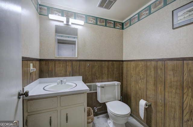 bathroom featuring wood walls, toilet, and vanity