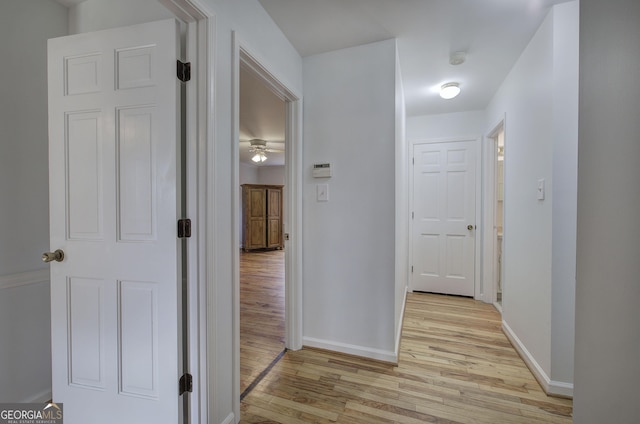 hall with light wood-style flooring and baseboards