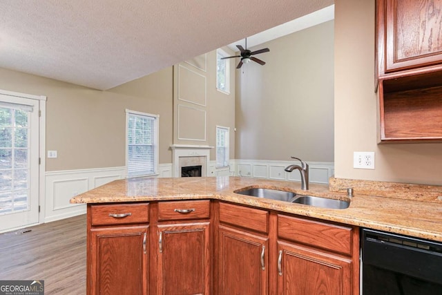 kitchen featuring dishwasher, sink, hardwood / wood-style flooring, ceiling fan, and light stone counters