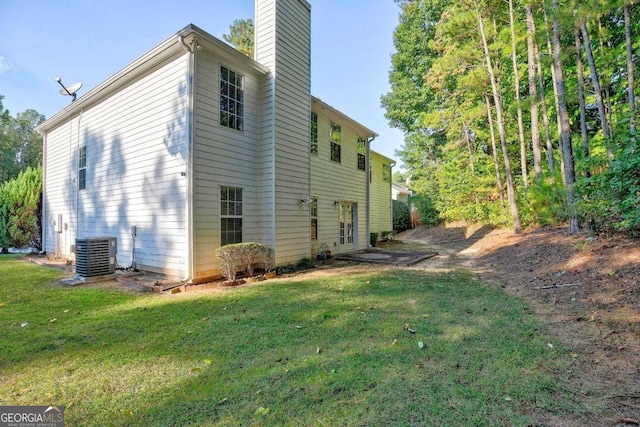 rear view of property featuring central air condition unit and a lawn