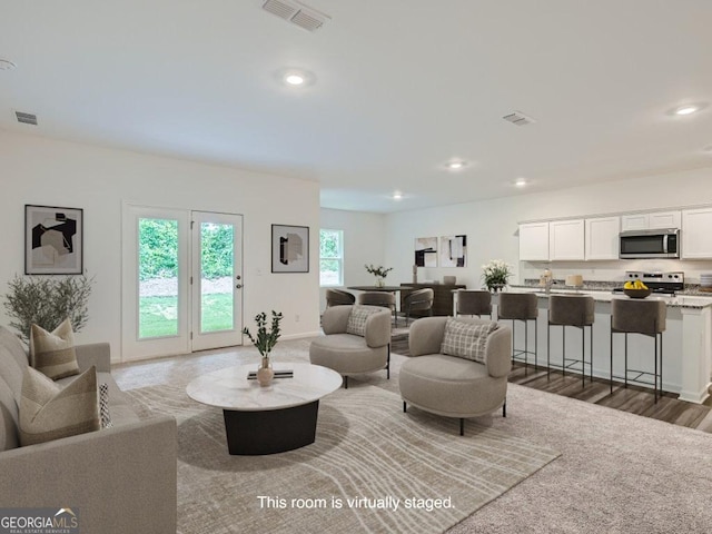 living area with baseboards, visible vents, and recessed lighting