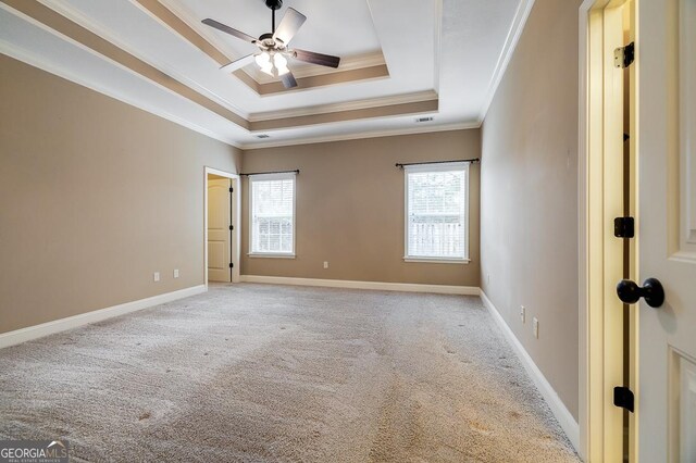 carpeted empty room featuring a raised ceiling, ceiling fan, and ornamental molding