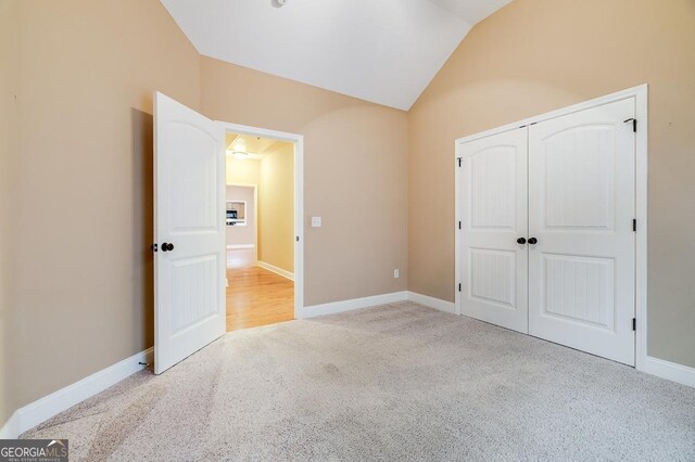 unfurnished bedroom with light carpet, a closet, and vaulted ceiling