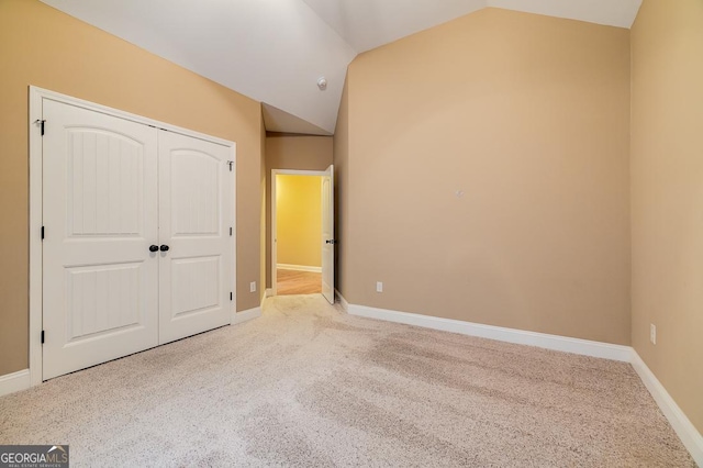 unfurnished bedroom featuring a closet, carpet, and lofted ceiling