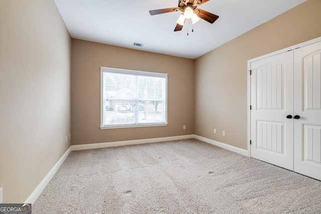 unfurnished bedroom featuring light carpet, a closet, and ceiling fan