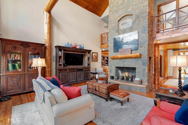 living room with a stone fireplace, hardwood / wood-style floors, high vaulted ceiling, and wooden ceiling