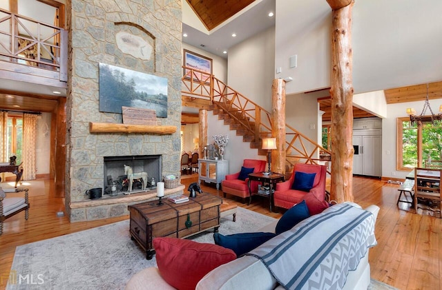 living room with hardwood / wood-style floors, a stone fireplace, wooden ceiling, and high vaulted ceiling