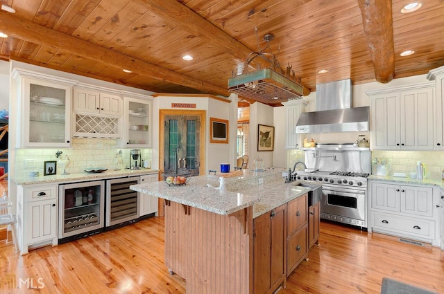 kitchen with white cabinets, wall chimney range hood, and wine cooler