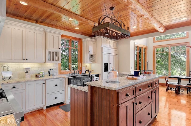 kitchen featuring a kitchen island, beam ceiling, paneled built in fridge, light hardwood / wood-style floors, and white cabinetry