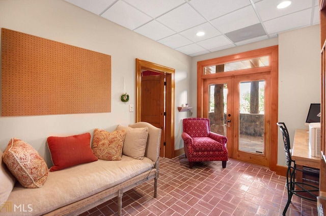 sitting room with a drop ceiling and french doors