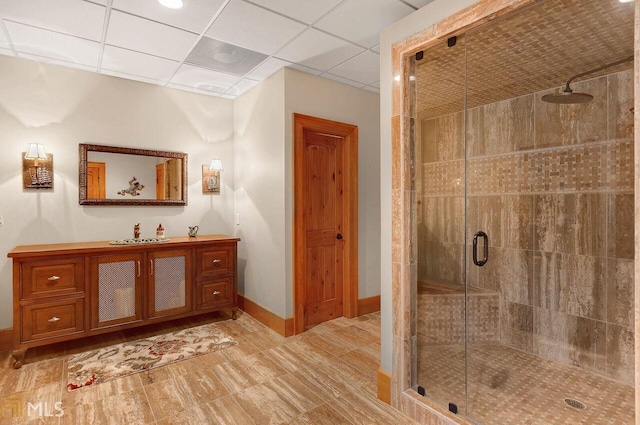 bathroom featuring a paneled ceiling, vanity, and an enclosed shower