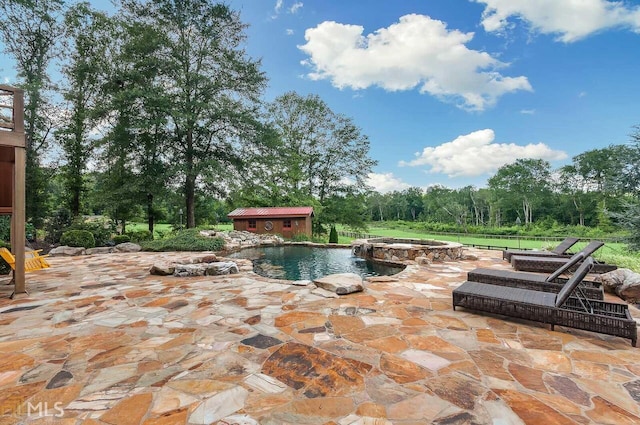 view of swimming pool featuring a patio area, an in ground hot tub, and an outdoor structure