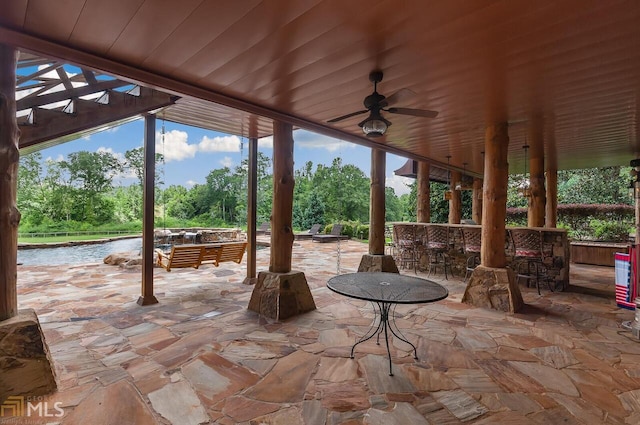 view of patio featuring ceiling fan, a water view, and a bar