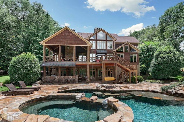 rear view of house featuring a patio, a balcony, and a pool with hot tub