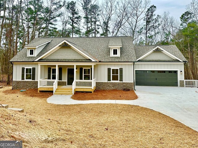 craftsman inspired home with a porch, a shingled roof, concrete driveway, an attached garage, and board and batten siding