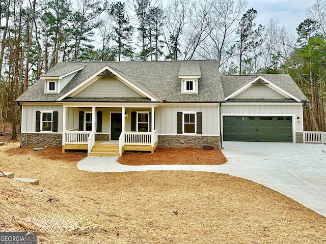 craftsman-style home featuring stone siding, a porch, board and batten siding, roof with shingles, and a garage