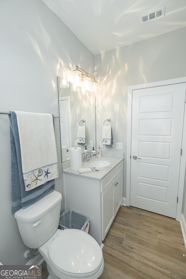 bathroom featuring wood-type flooring, vanity, and toilet