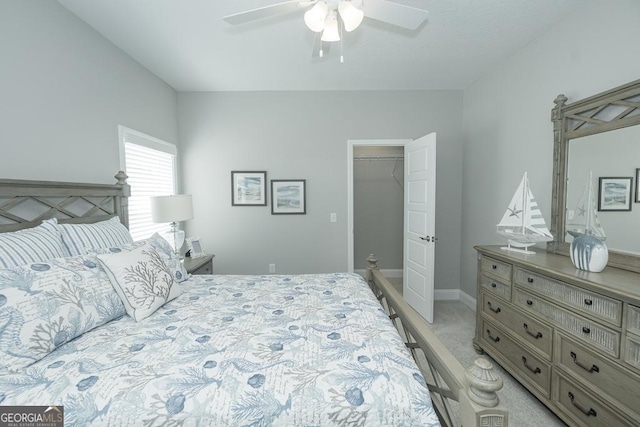 bedroom featuring ceiling fan, a walk in closet, light carpet, and a closet