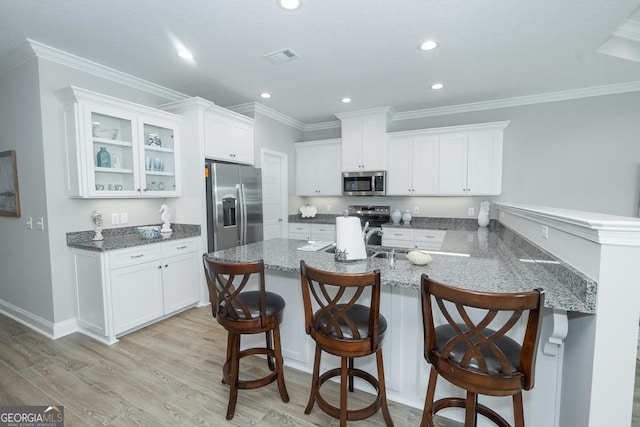 kitchen featuring kitchen peninsula, a kitchen breakfast bar, stainless steel appliances, white cabinets, and light hardwood / wood-style floors