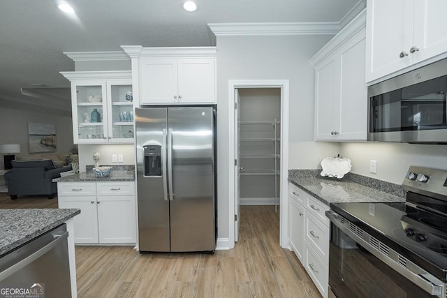 kitchen featuring appliances with stainless steel finishes, light hardwood / wood-style floors, dark stone counters, white cabinets, and ornamental molding