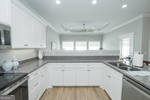 kitchen with appliances with stainless steel finishes, a raised ceiling, crown molding, sink, and white cabinets