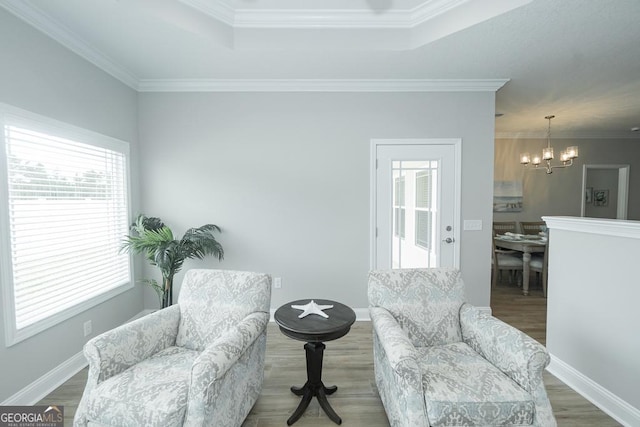 sitting room featuring a tray ceiling, crown molding, plenty of natural light, and an inviting chandelier