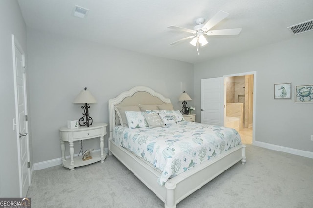 bedroom featuring ceiling fan, light colored carpet, and connected bathroom