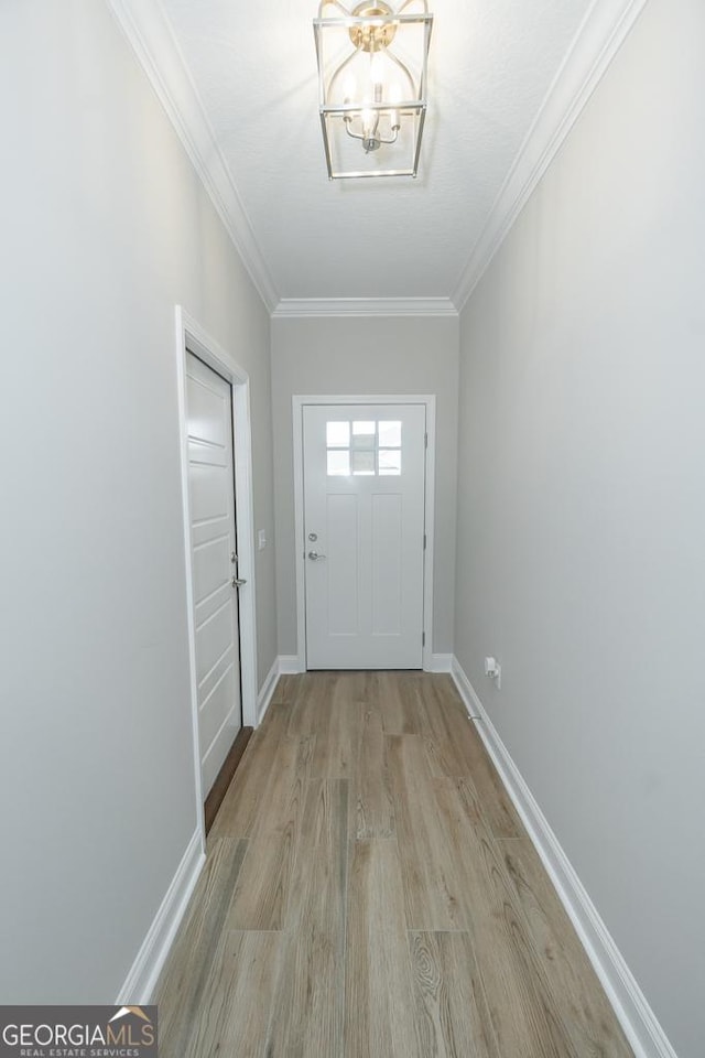 doorway to outside featuring an inviting chandelier, crown molding, and light hardwood / wood-style flooring