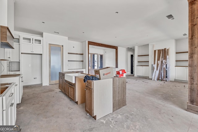 kitchen featuring white cabinets, a kitchen island, and sink